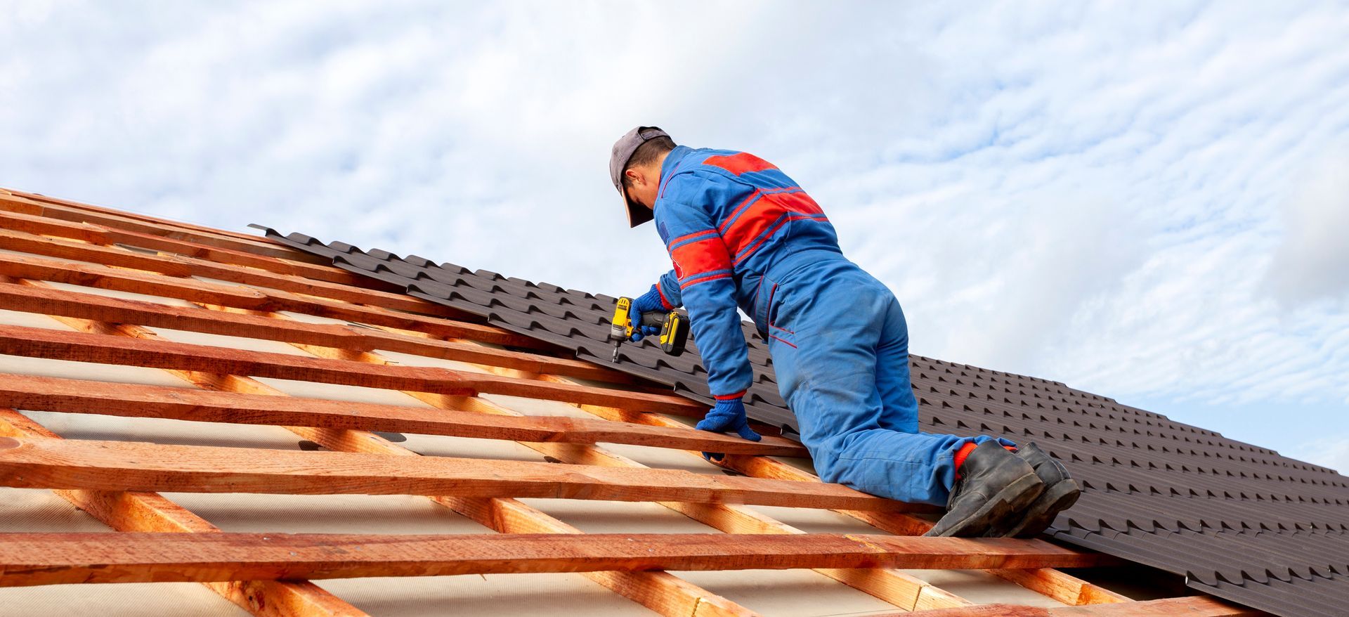 Roofing contractor installing metal roofing panels on a residential roof structure.