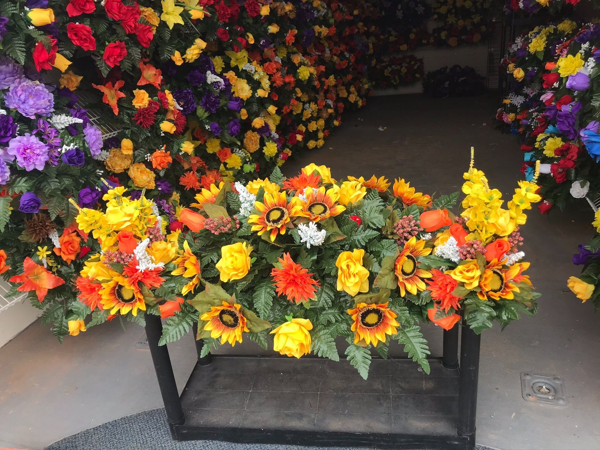 Flower stand with bright artificial sunflowers and mixed bouquets in a shop display.