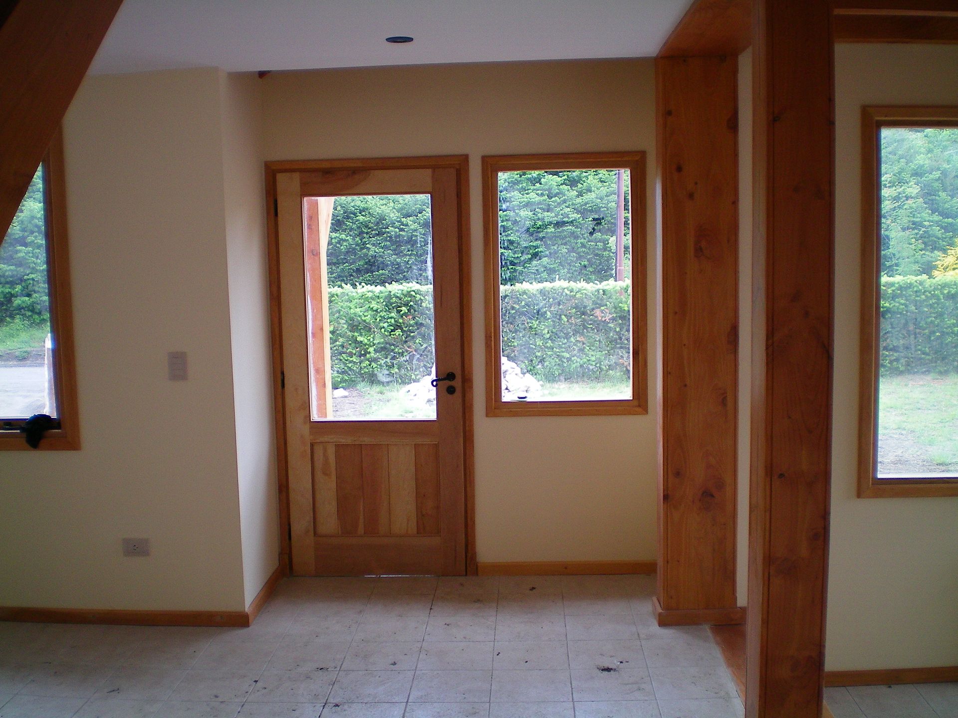 Muebles de madera hechos a medida con estantes blancos divididos en secciones, sobre una pared lisa y suelo de baldosas.
