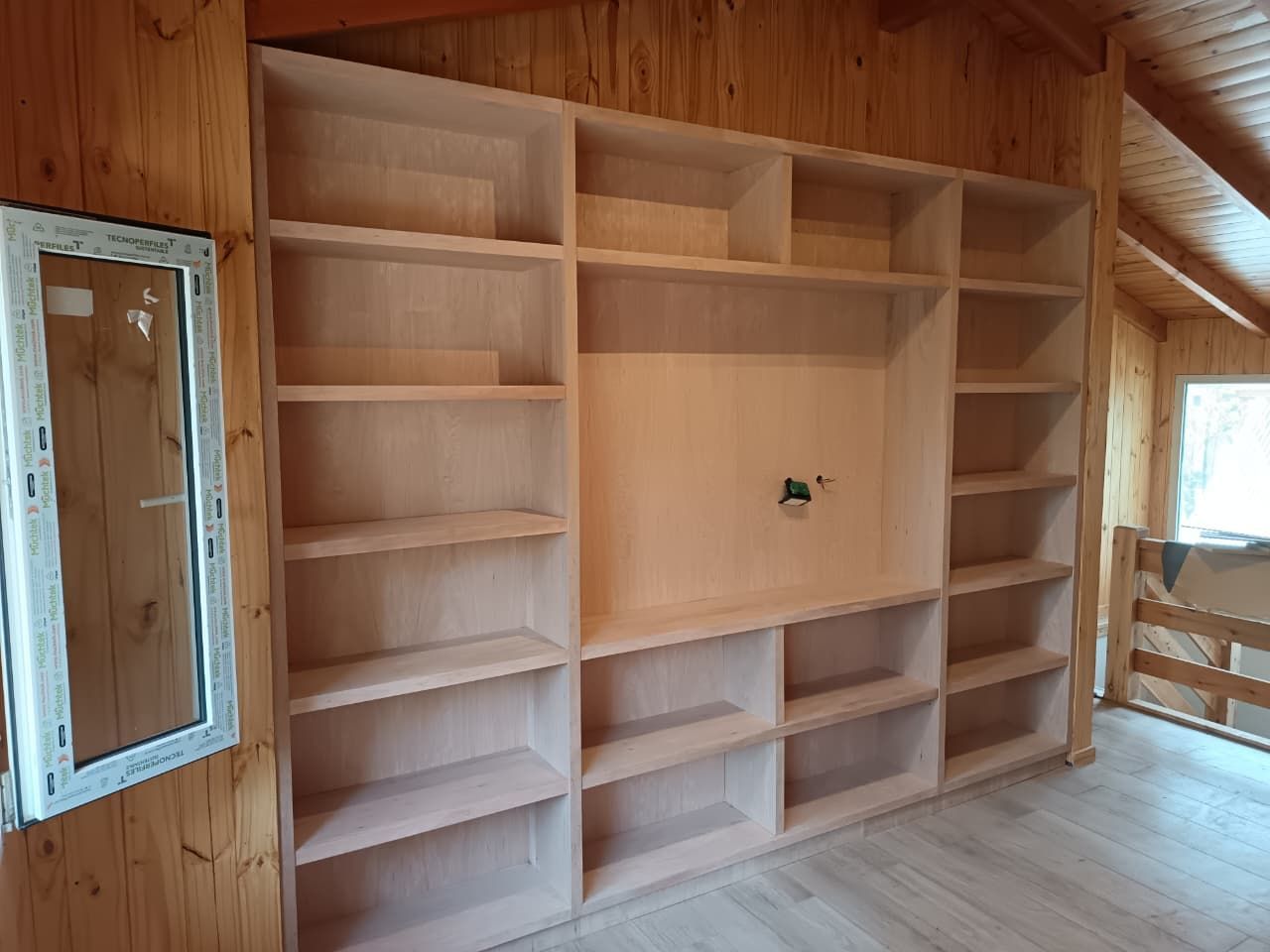 Estanterías de madera hechas a medida, integradas en el espacio bajo una escalera moderna.