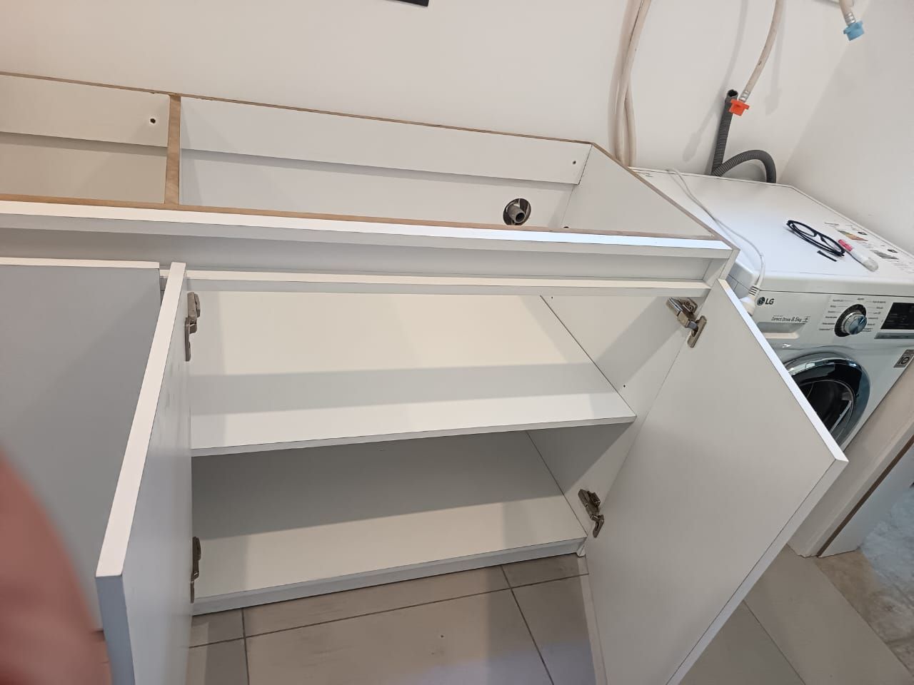 Armario de madera con estantes abiertos para guardar ropa doblada y cajas de almacenamiento, además de tres cajones en la parte inferior.