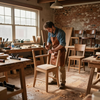 Un carpintero con delantal de cuero utiliza un martillo para ensamblar una silla de madera en un taller de carpintería rústico y soleado.