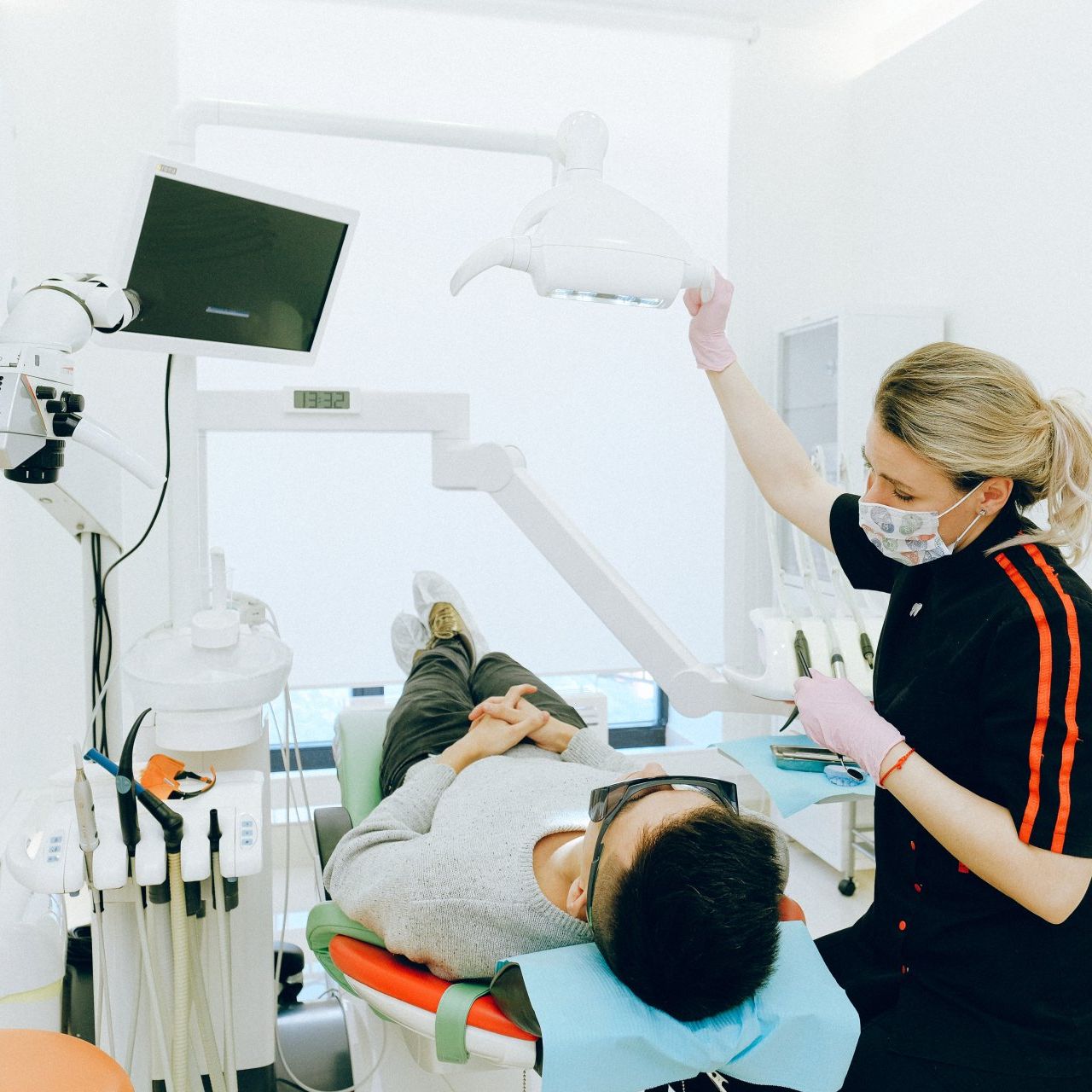 A man is laying in a dental chair while a woman stands behind him