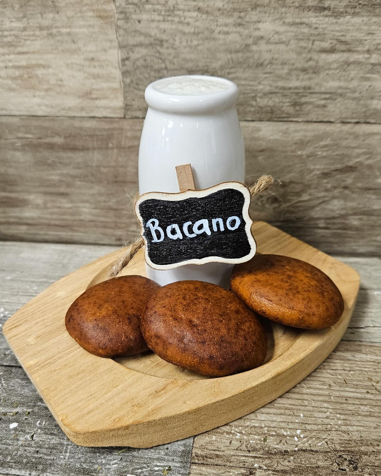A wooden cutting board topped with cookies and a jar of bacano.