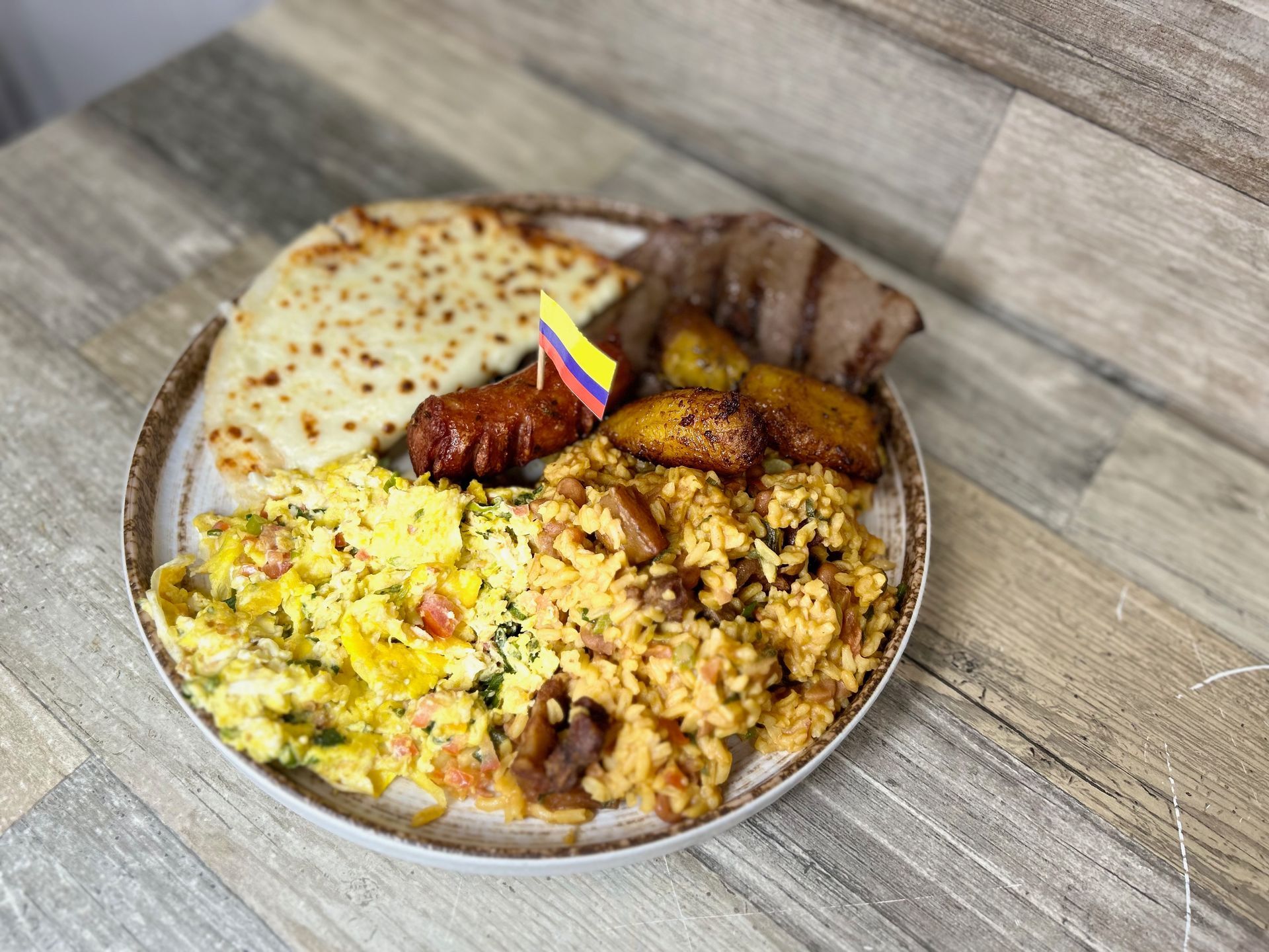 A plate of food with a flag on it is on a wooden table.