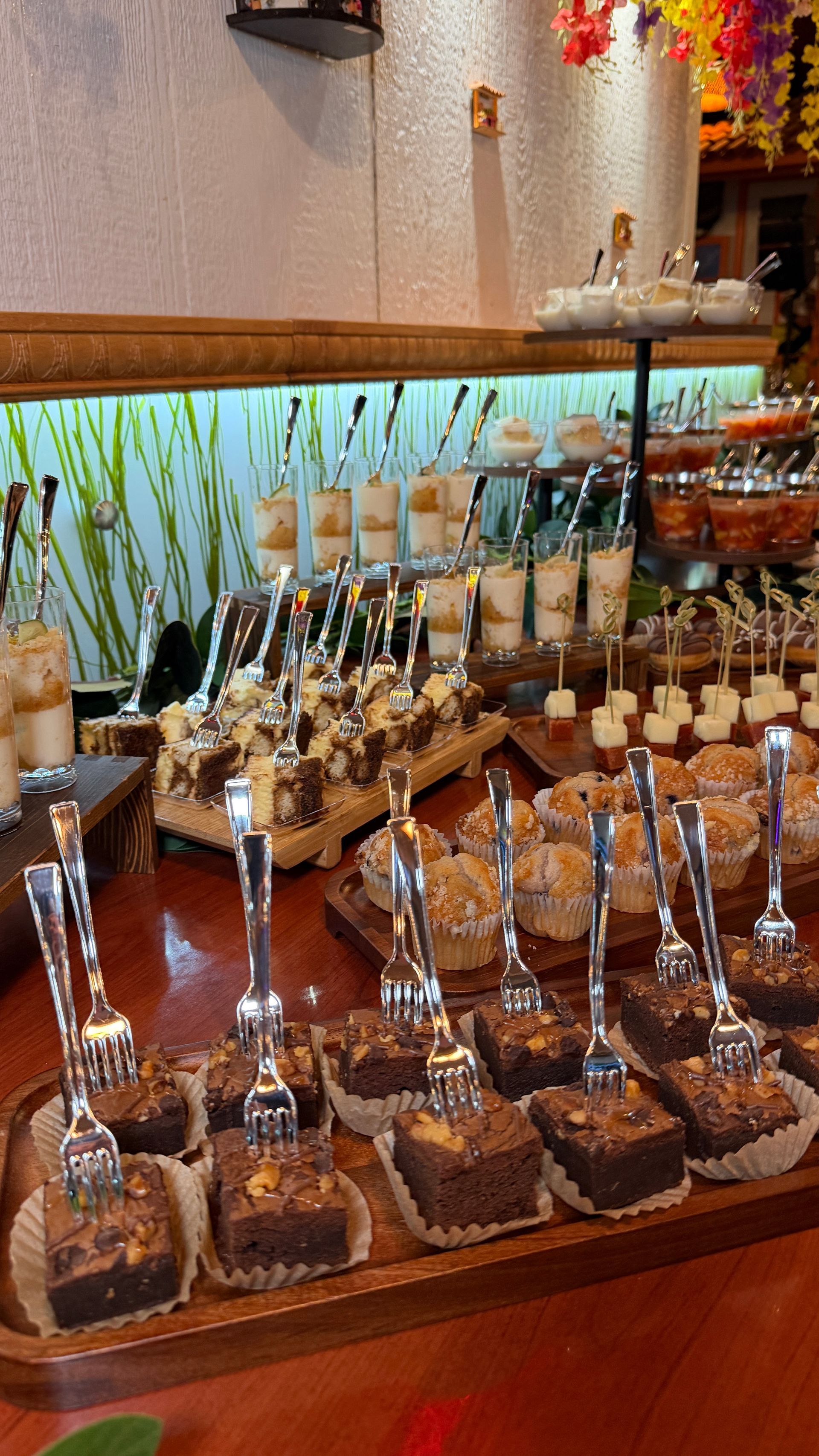 A dessert buffet with brownies, parfaits, and other treats, set on a wooden table.
