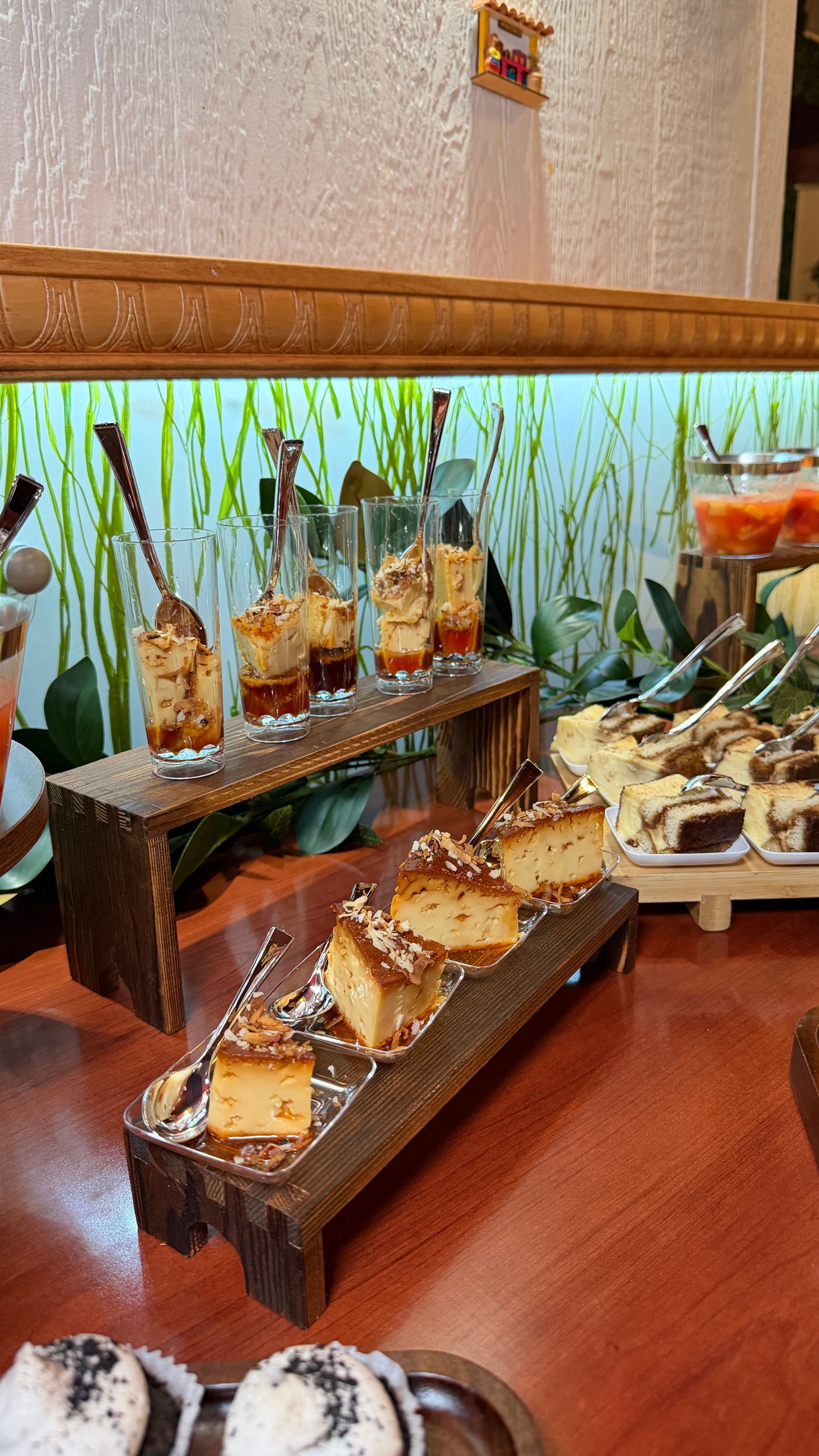 Dessert buffet: wooden platters with mini cakes, parfaits, and sweets. Colorful background.