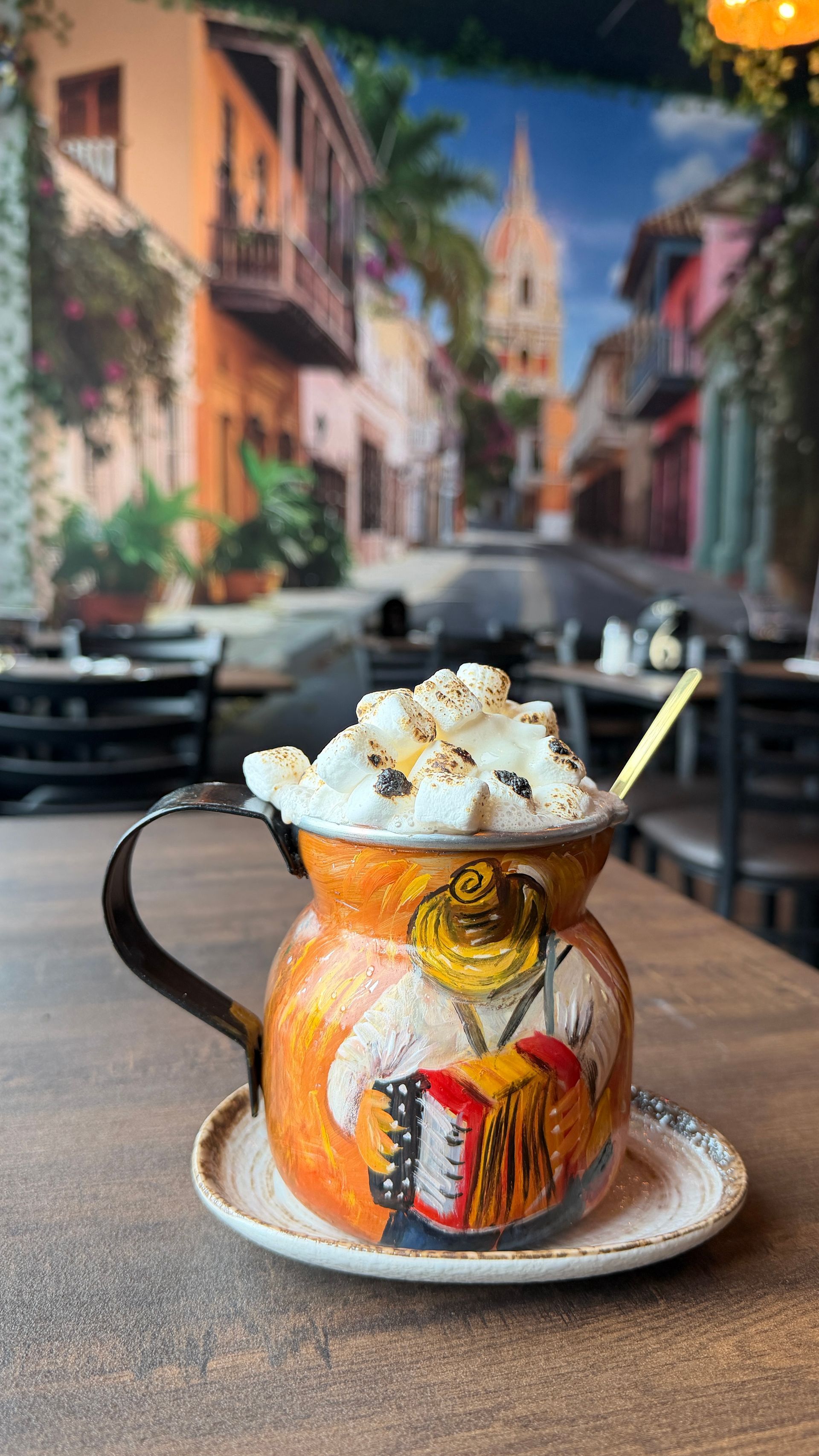 Hot drink in a colorful decorated mug with whipped cream, on a saucer.