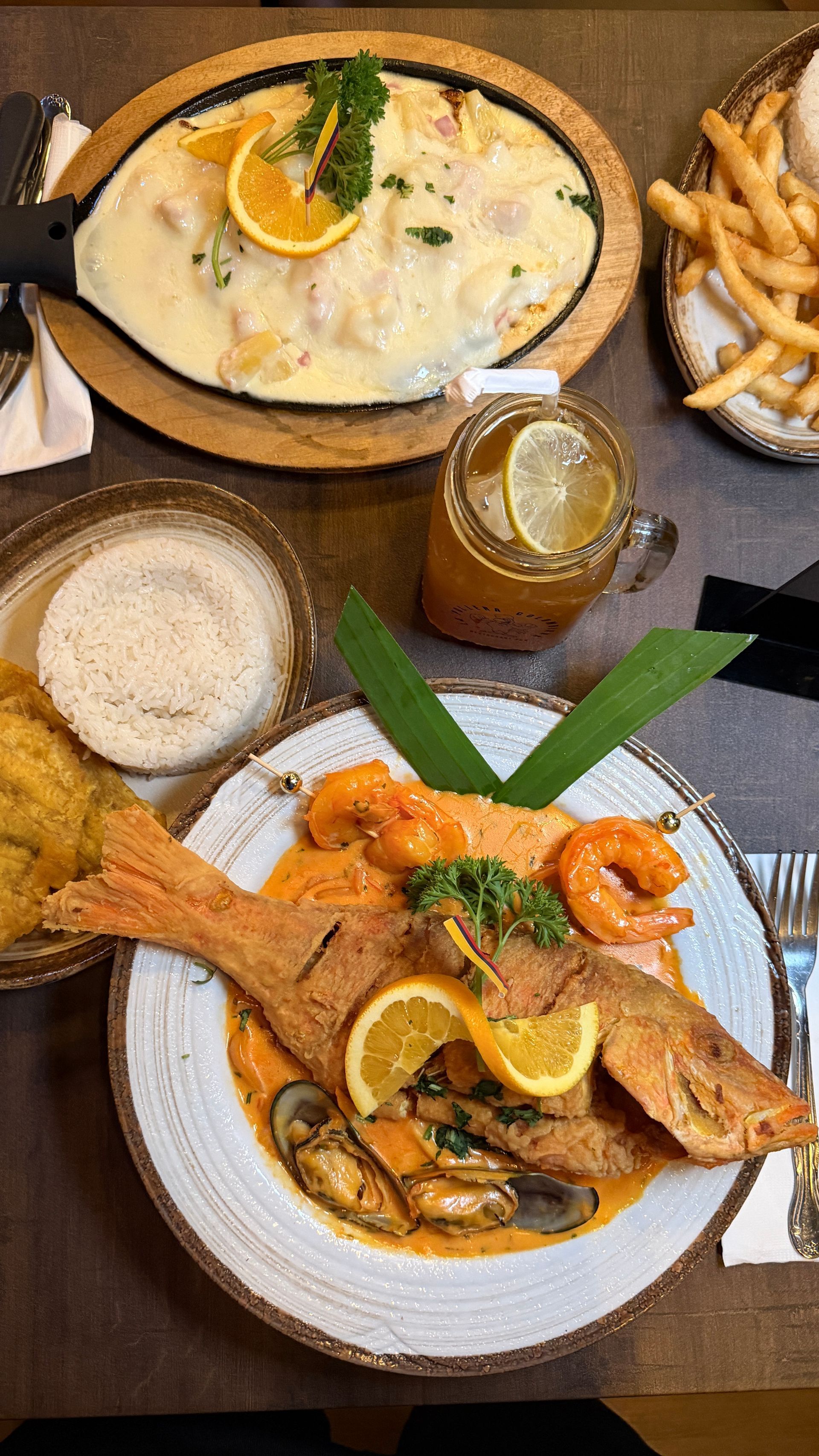 Overhead view of a seafood meal including fish, shrimp, fries, rice, and a drink.