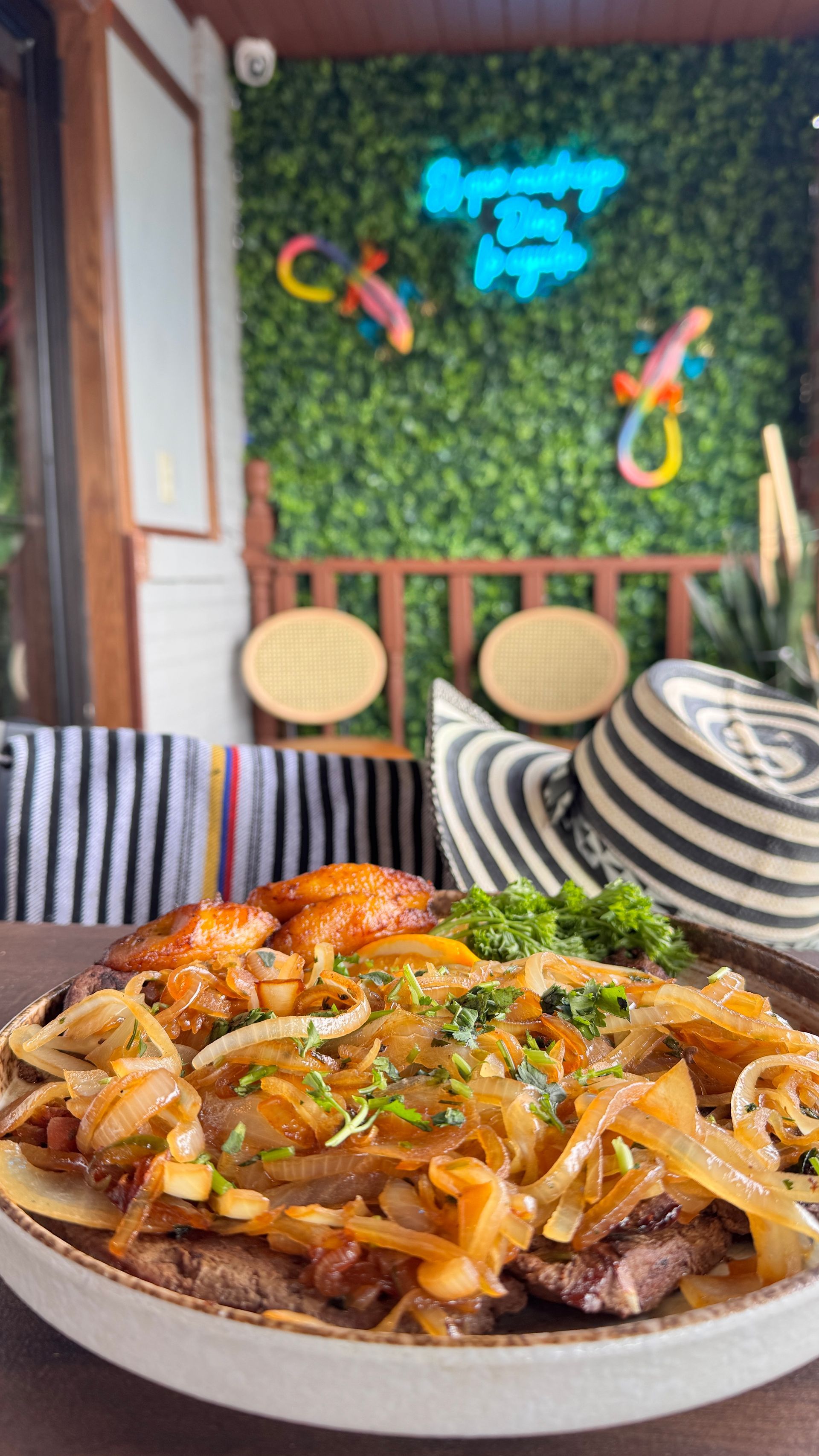 Plate of food with cooked onions, meat, chicken, and broccoli, in a restaurant setting.