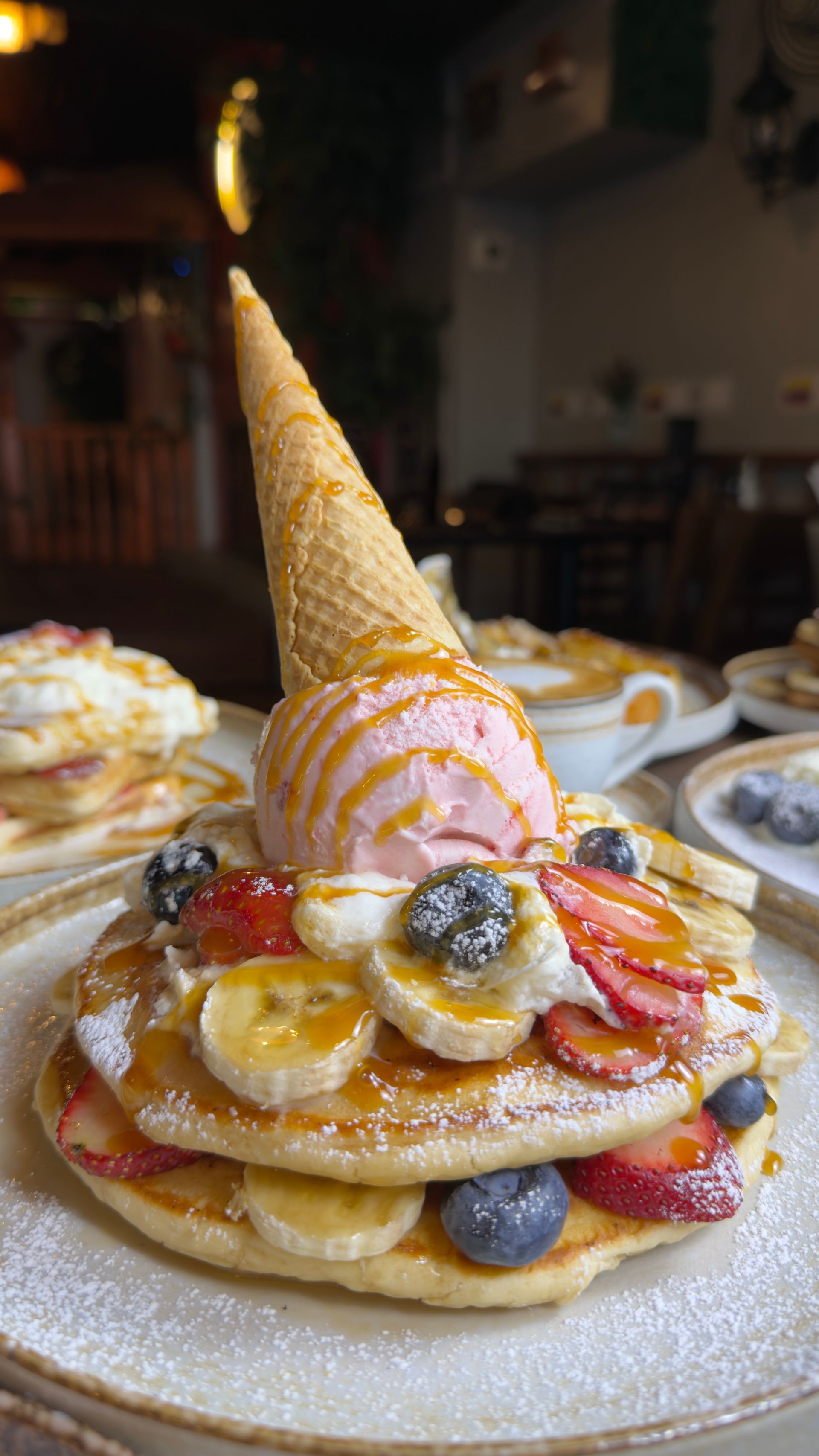 Stack of pancakes topped with strawberries, blueberries, banana slices