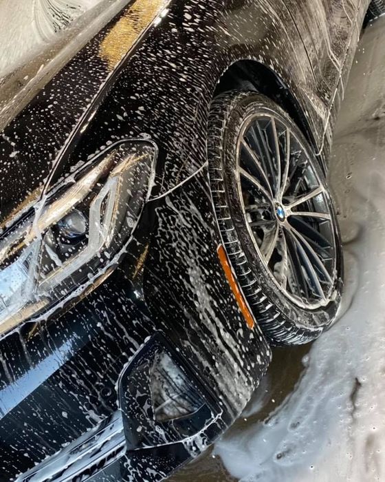 A black car is covered in soap and water.