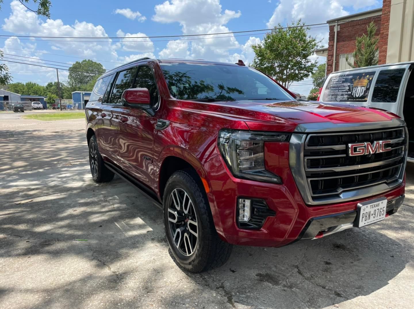 A red gmc yukon is parked on the side of the road.