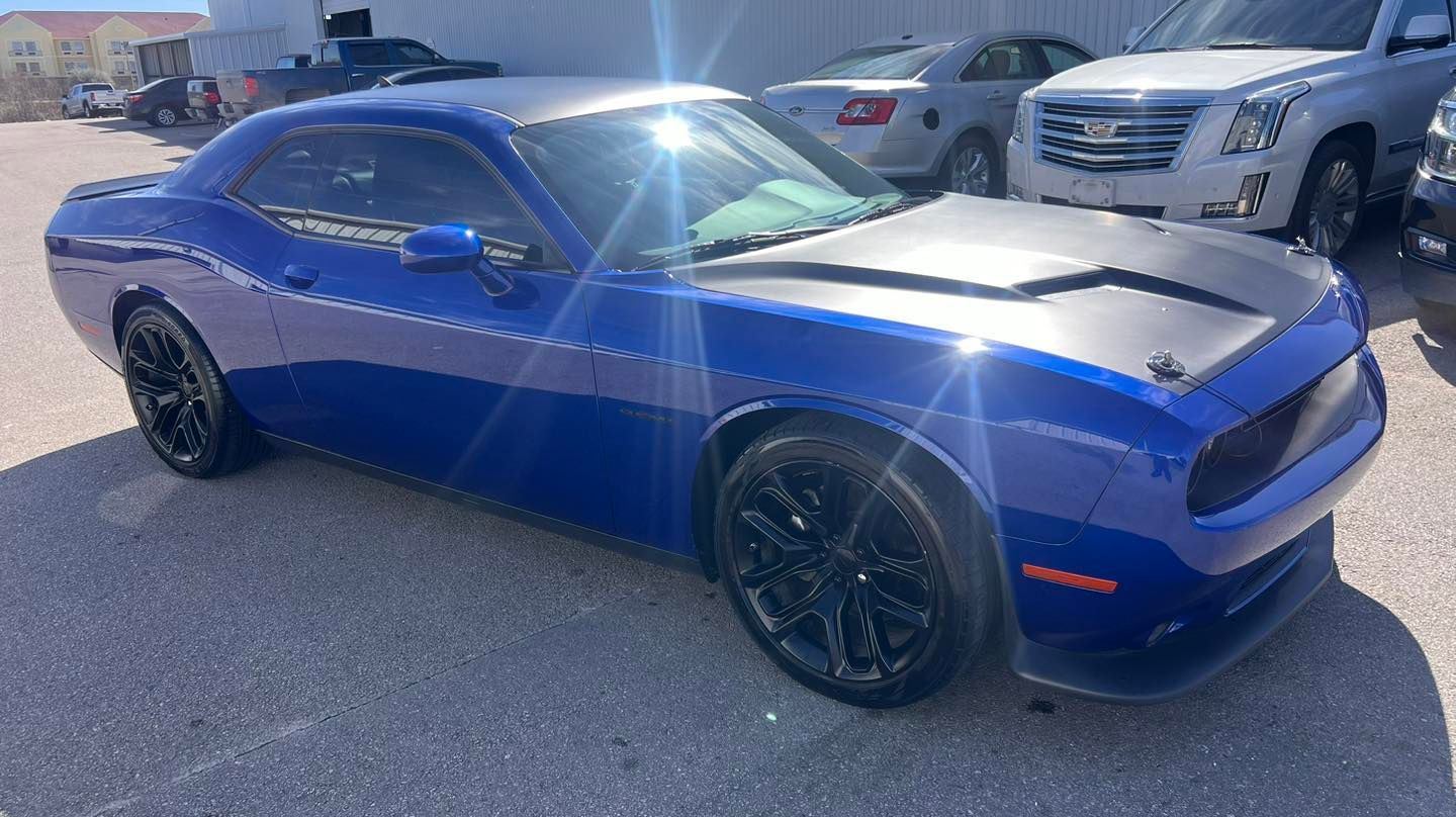 A blue dodge challenger is parked in a parking lot.