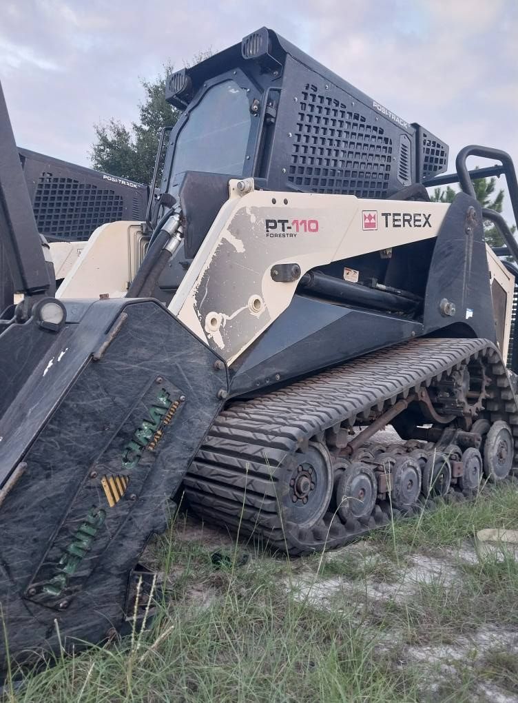 Terex PT-110 compact track loader with a forestry mulcher attachment, off-white and black.