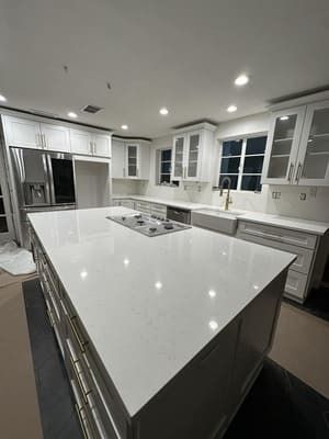 Bright modern kitchen with white island, stainless appliances, and recessed ceiling lights