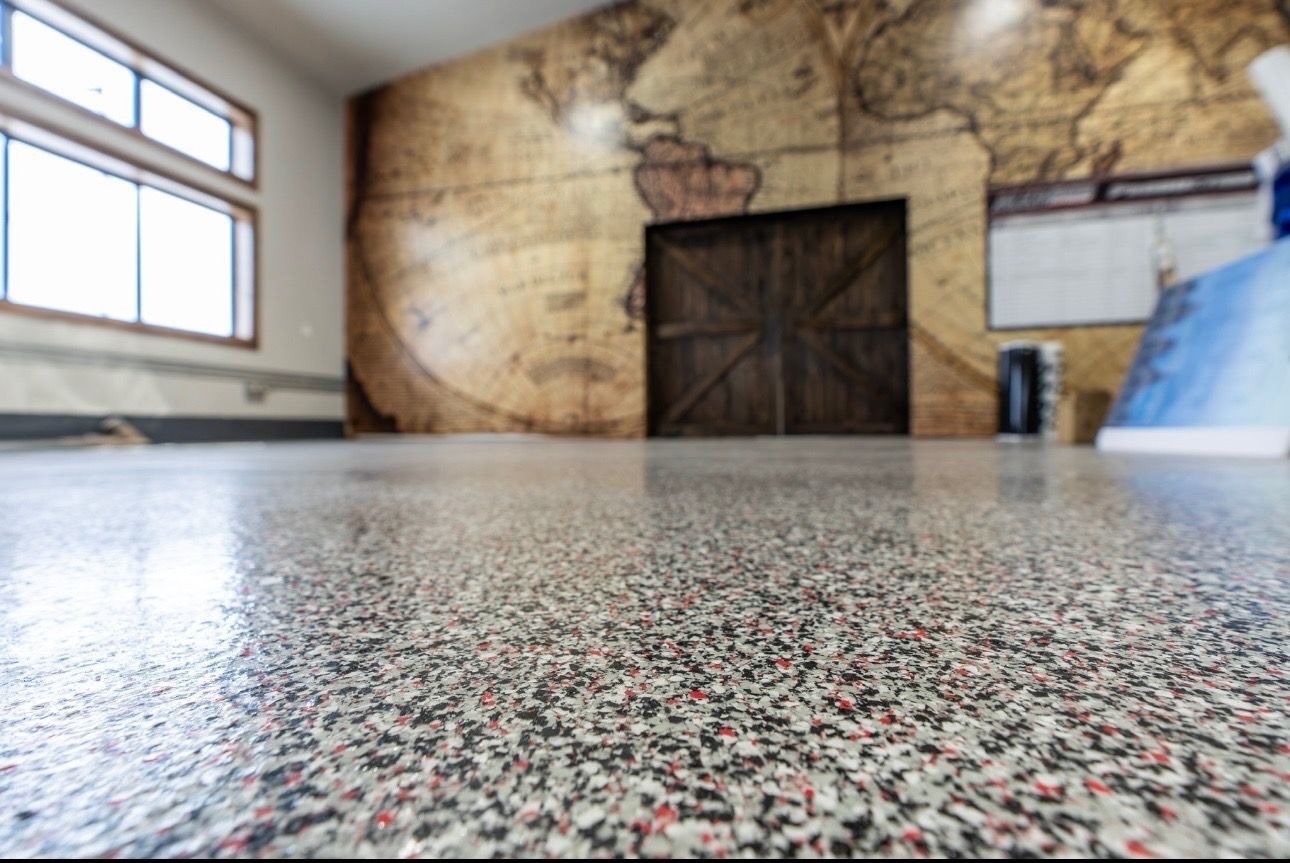 Low-angle view of a speckled floor in a room with a large mural wall and window.