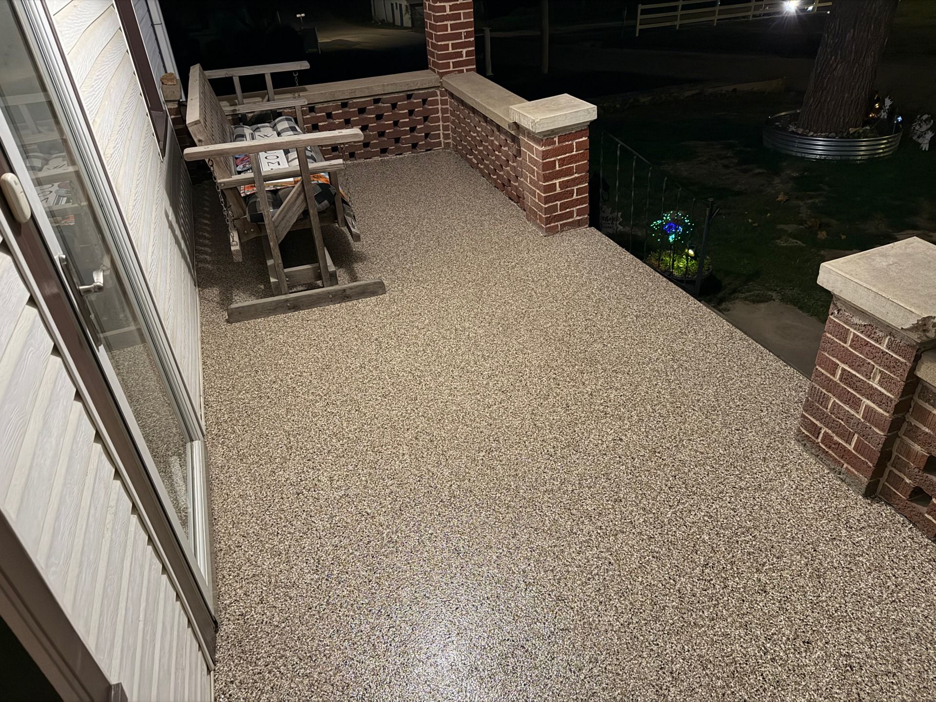 Gravel-covered porch with brick railing, picnic table, and steps leading to a dark yard at night