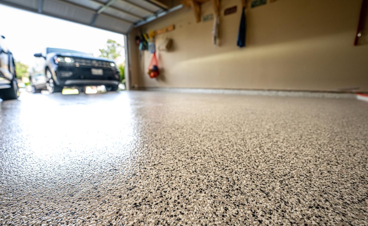 Low-angle view of a garage floor with a parked car near the open door