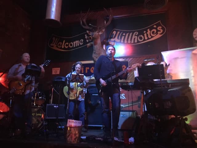 A man playing a guitar in front of a sign that says welcome