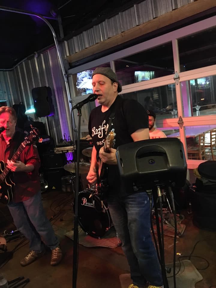 A man is singing into a microphone while playing a guitar.