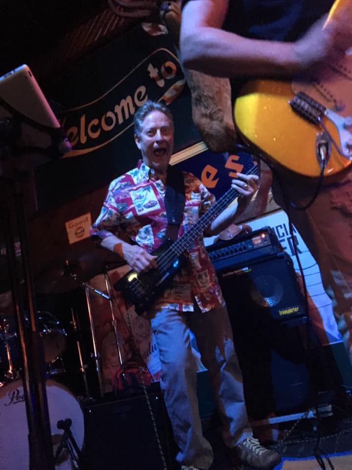 A man playing a guitar in front of a welcome sign