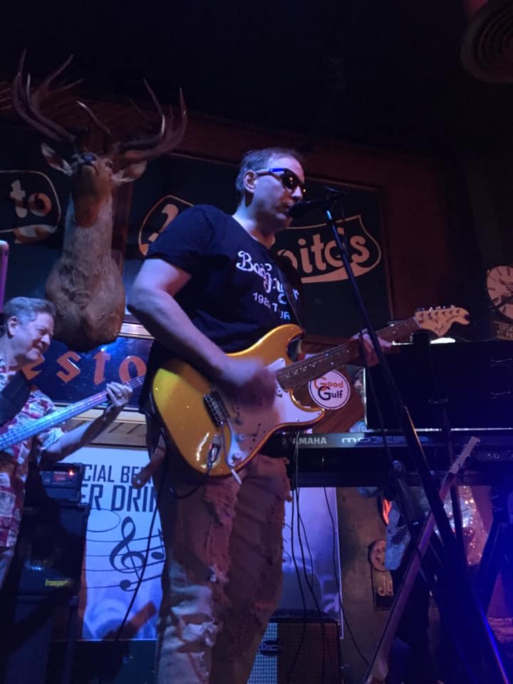 A man is playing a guitar and singing into a microphone on a stage.