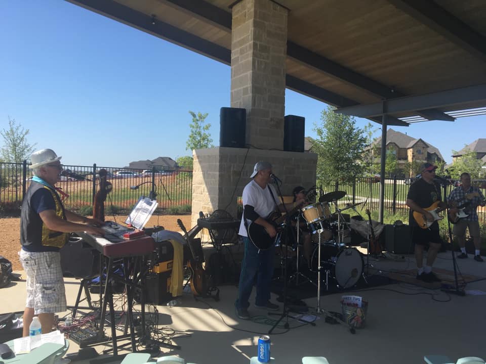 A group of men are playing instruments on a stage under a canopy.