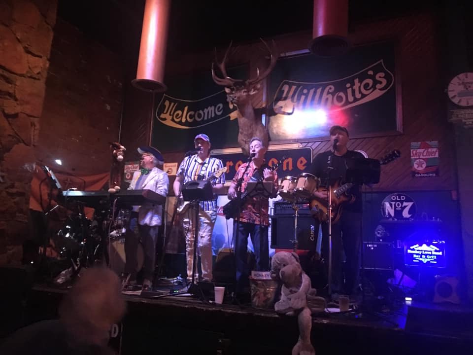 A group of people are playing instruments on a stage in a dark room.
