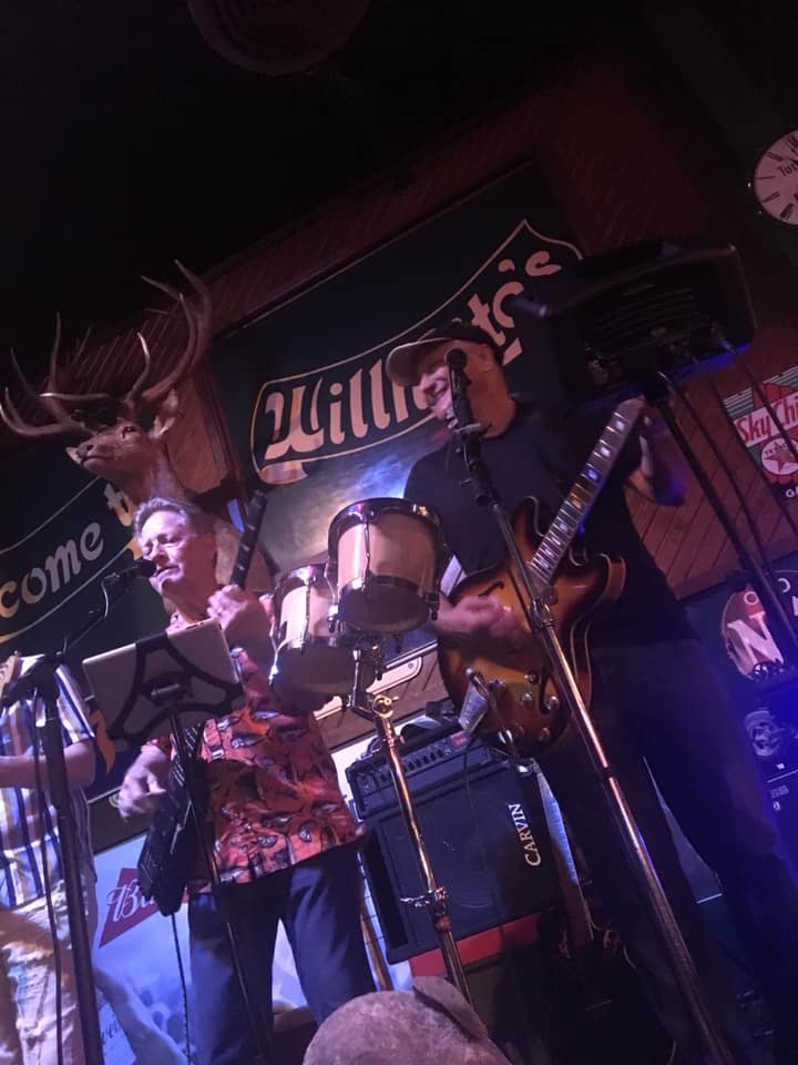A group of people are playing instruments on a stage in a dark room.