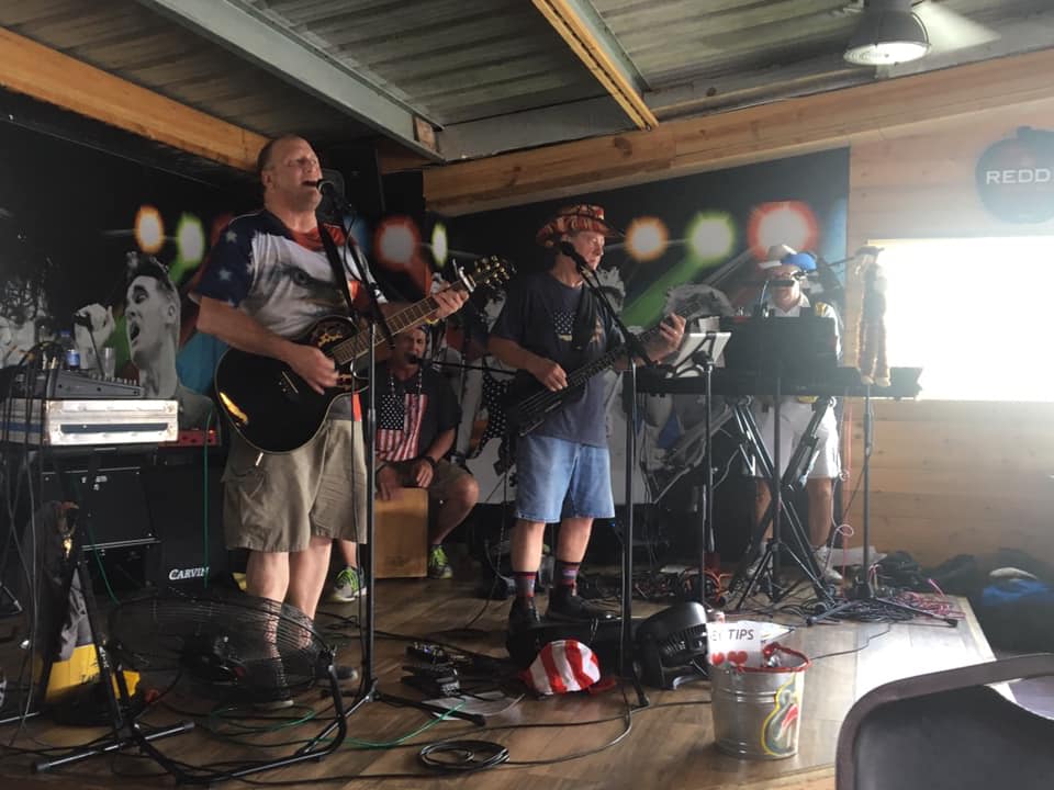 A group of men are playing guitars and singing into microphones on a stage.