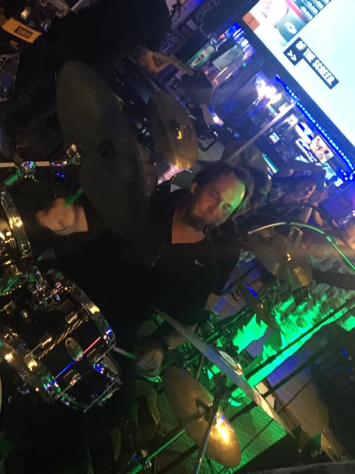 A man is playing drums in front of a large screen