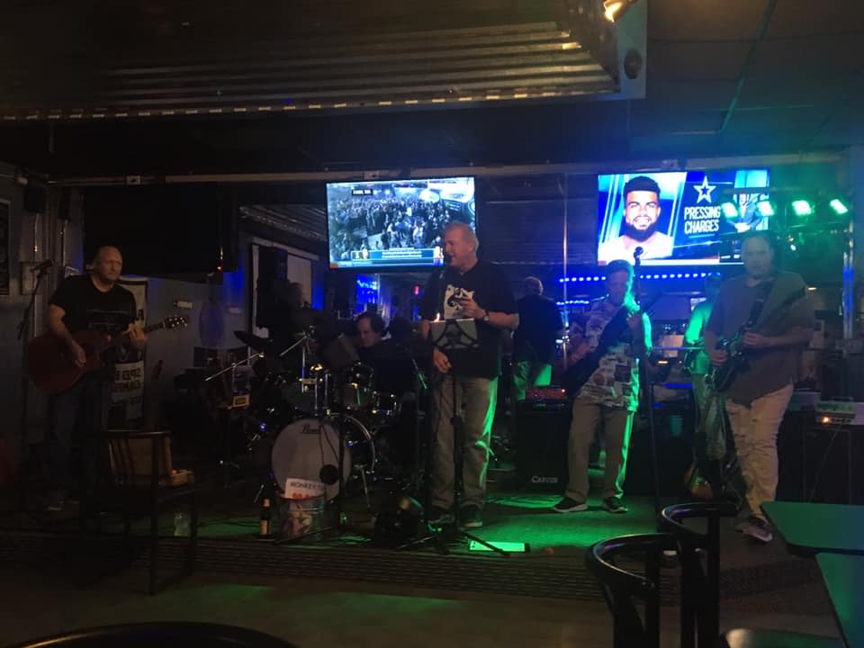 A group of people are playing instruments on a stage in a bar.