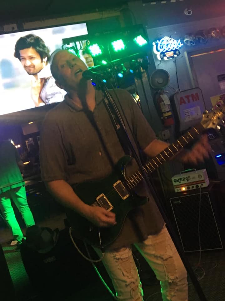 A man singing into a microphone while playing a guitar