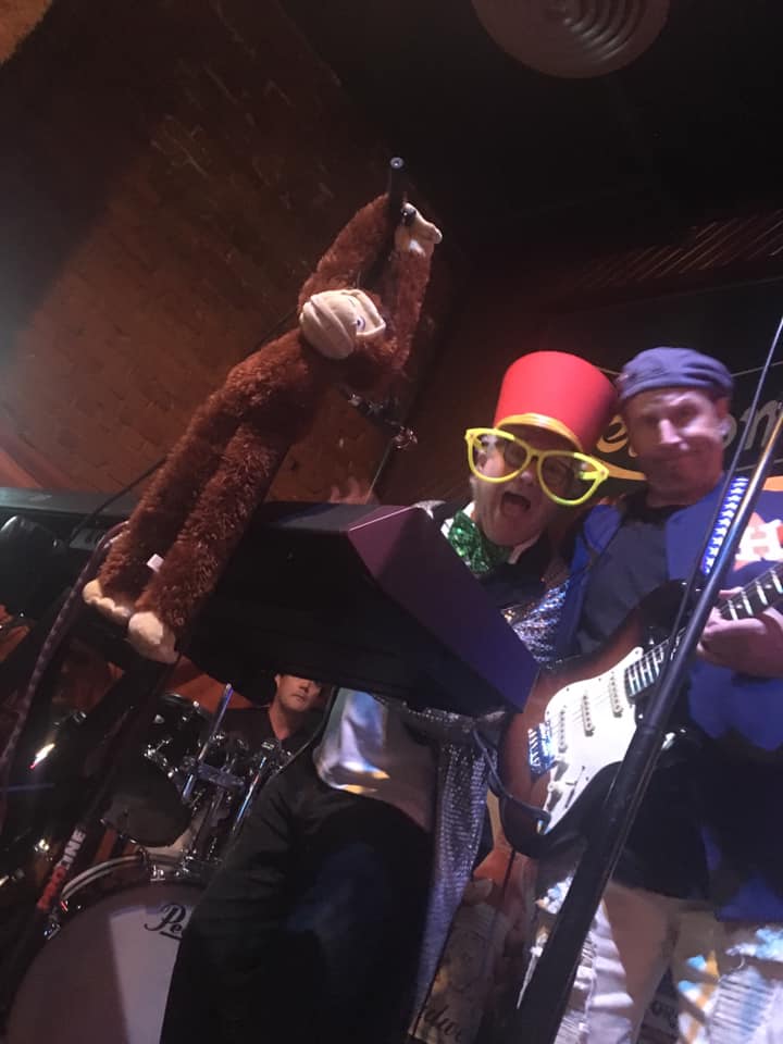 A man is holding a stuffed monkey while playing a guitar.