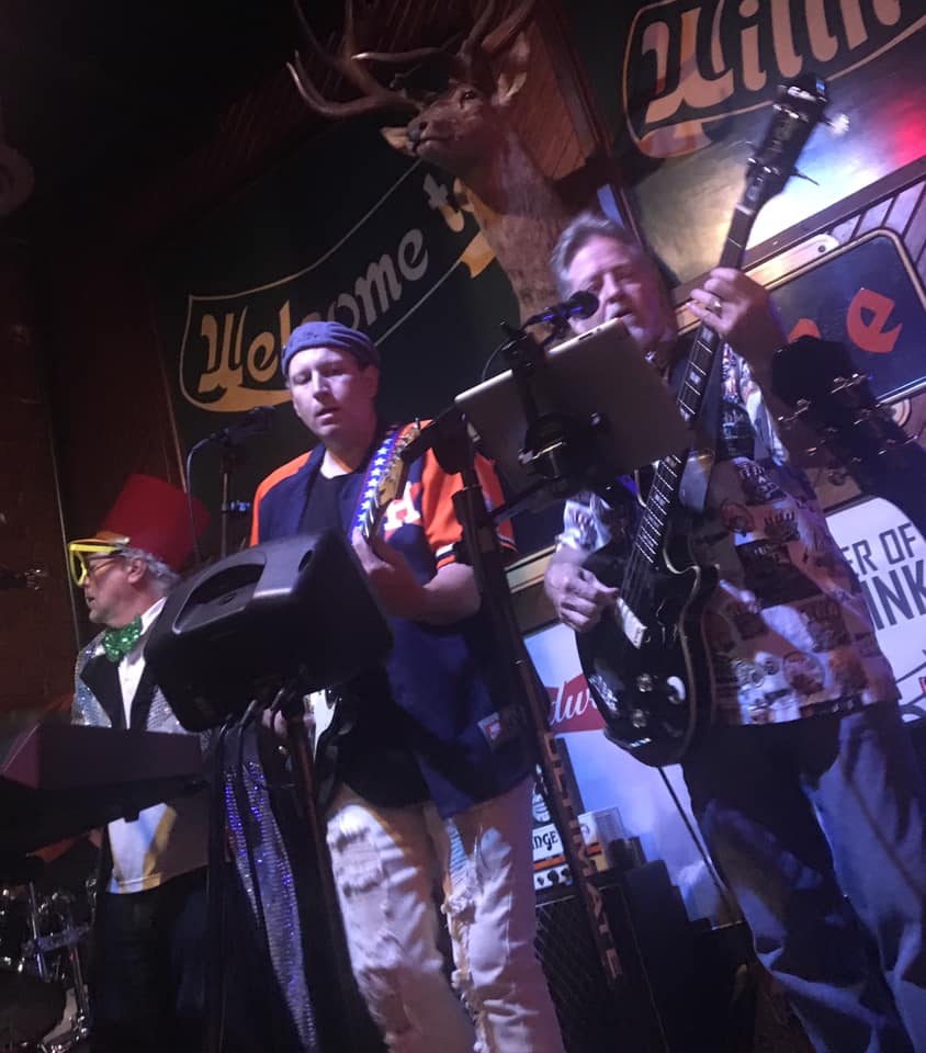 A man playing a guitar in front of a sign that says welcome