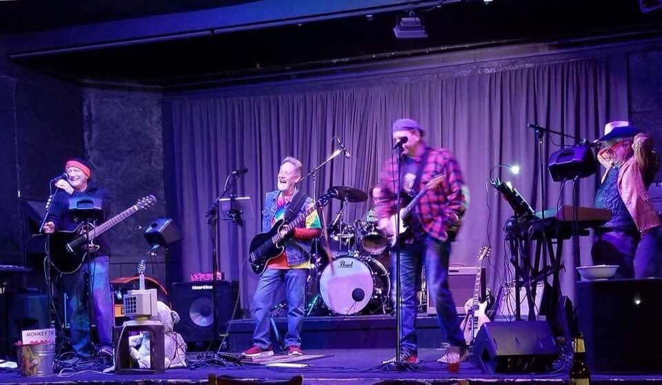 A group of people are standing on a stage playing instruments.