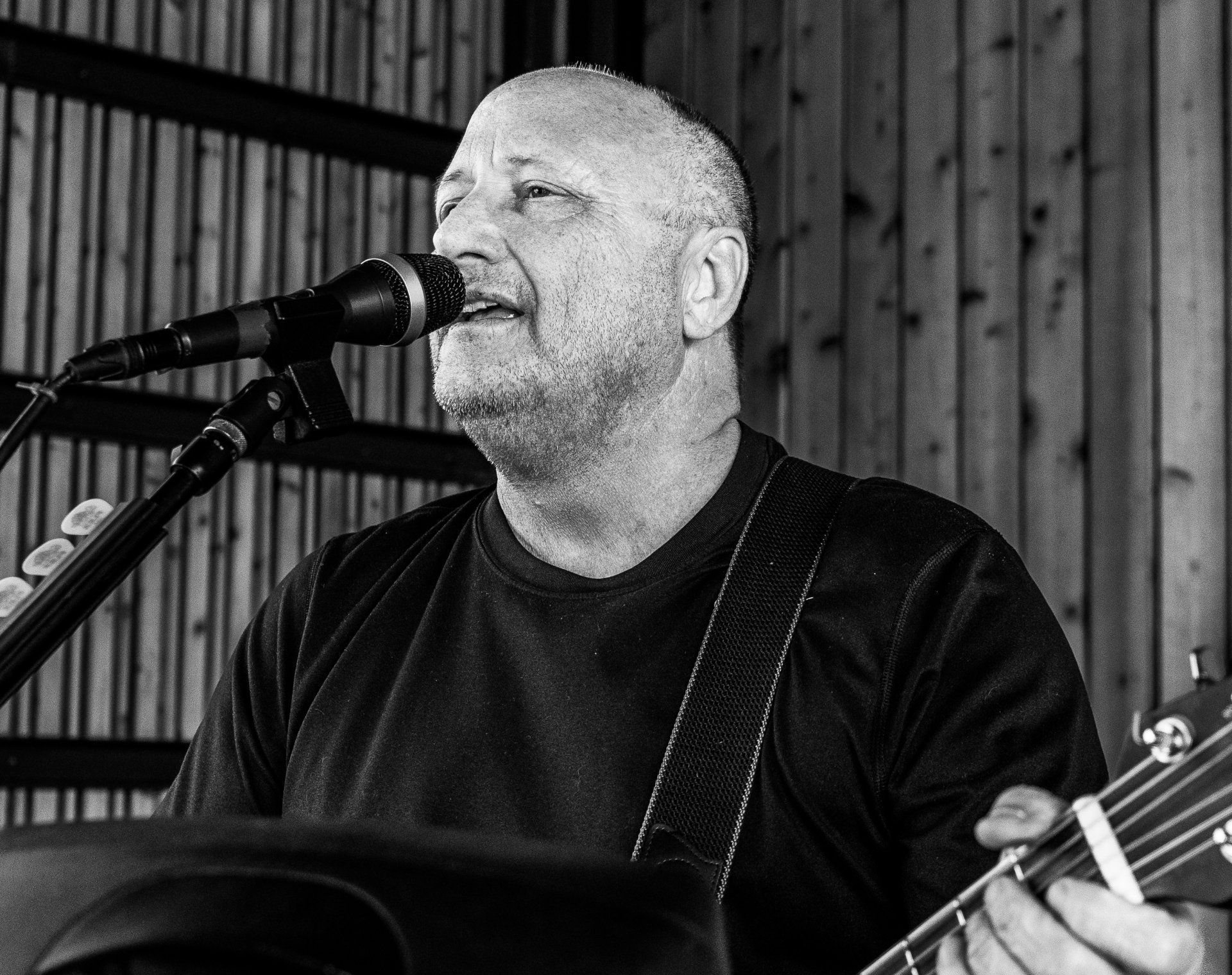 A man is singing into a microphone while holding a guitar.