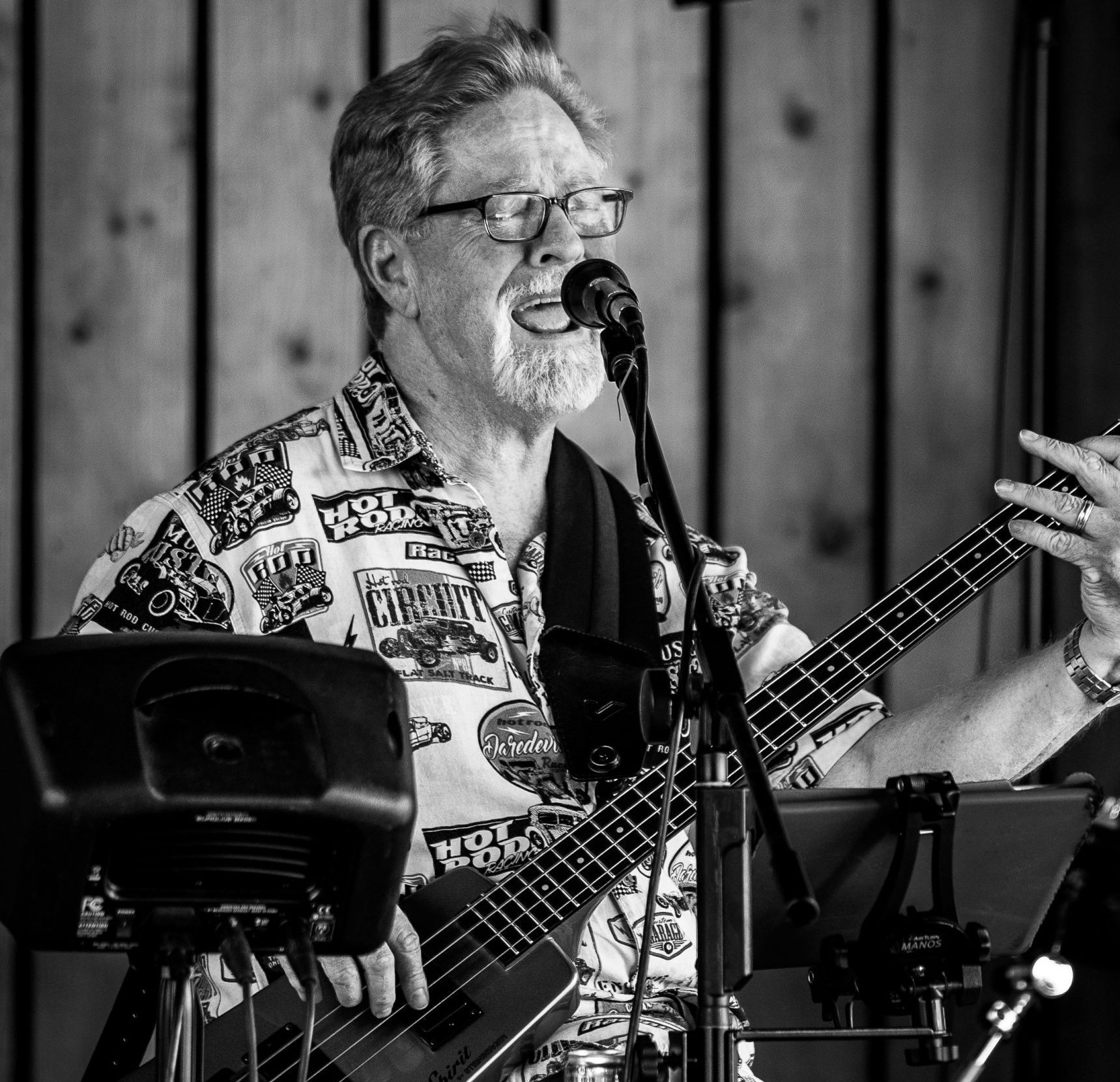 A man is singing into a microphone while playing a bass guitar.