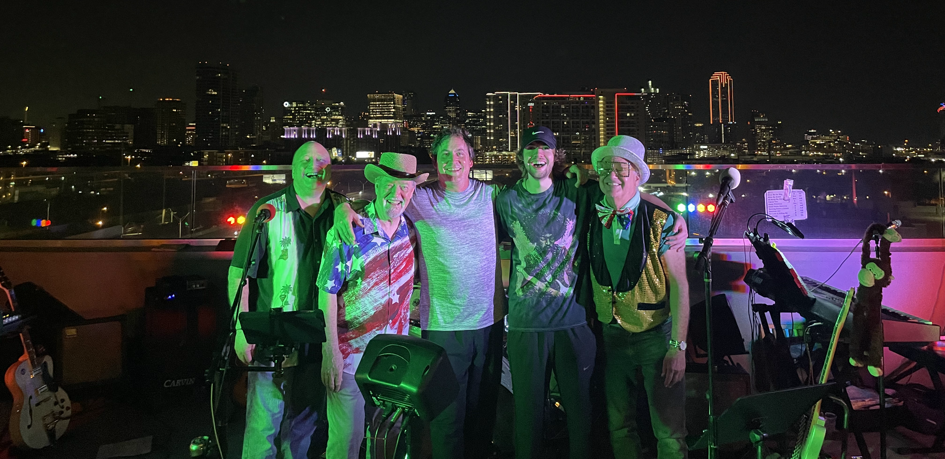 A group of men are posing for a picture in front of a city skyline at night.