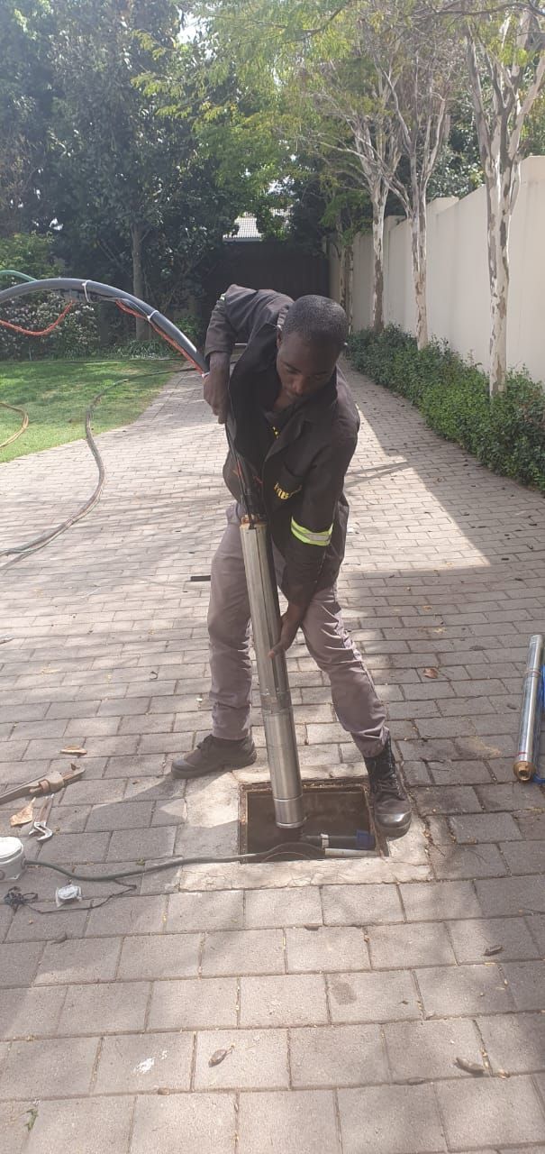 A man is digging a hole in the ground with a hose.