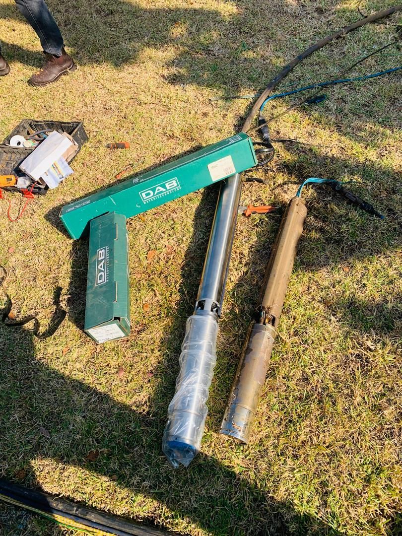 A couple of water pumps sitting on top of a lush green field.