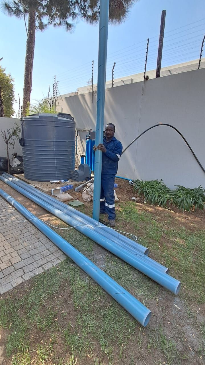 A man is standing next to a pole holding a hose.