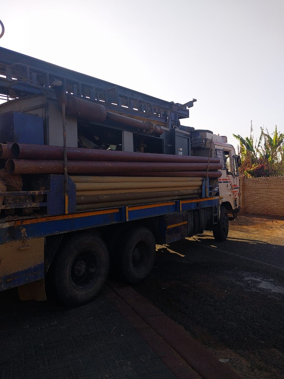 A truck loaded with pipes is parked on the side of the road.