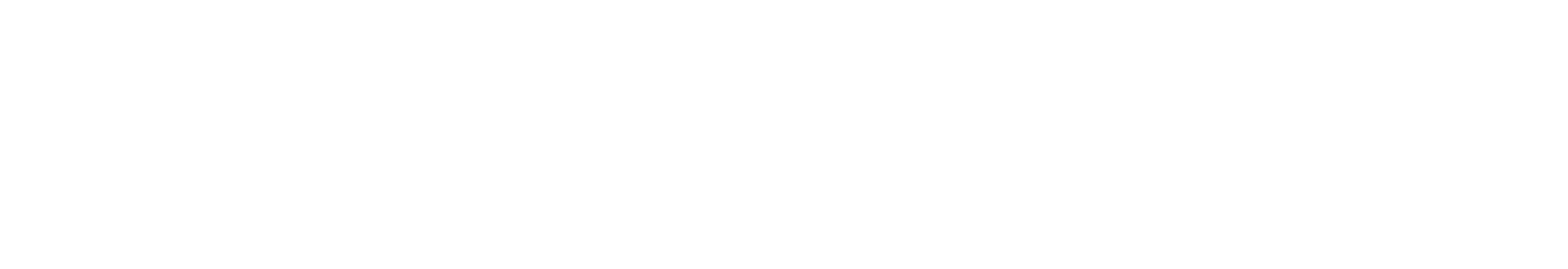 A group of people wearing bright, patterned traditional attire posing for a photo outdoors in a garden setting.