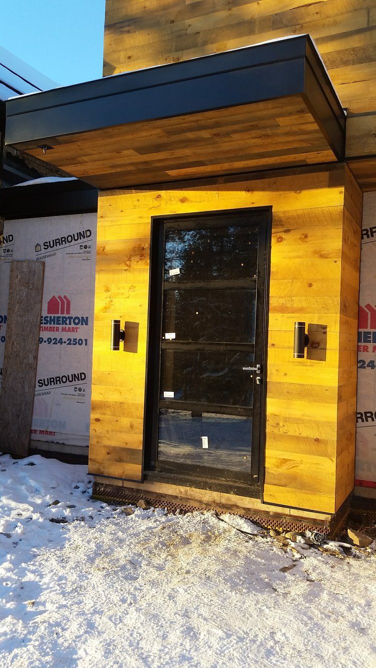 A wooden door with a canopy over it is sitting in the snow.
