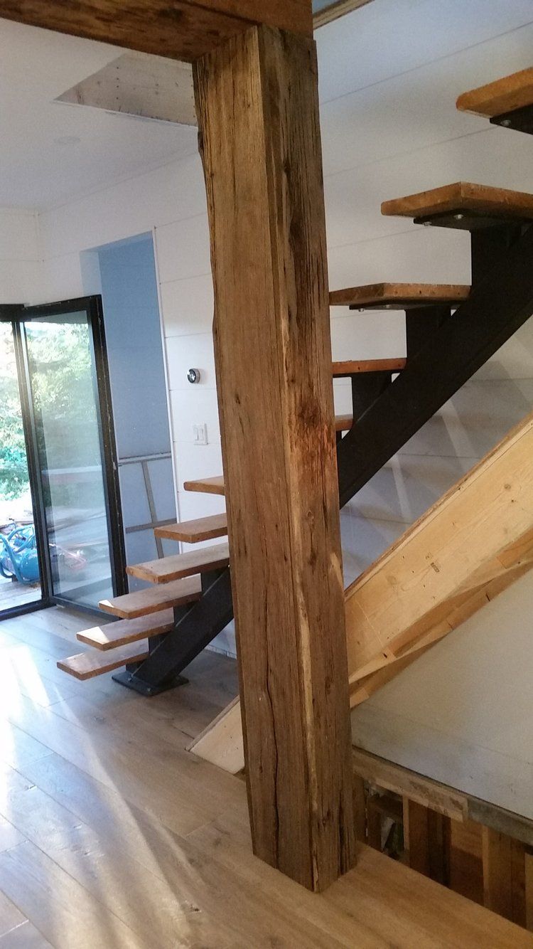 A wooden staircase with a wooden post in the middle of a room.