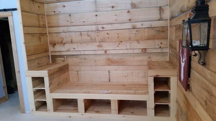 A wooden bench in a room with a lantern on the wall.