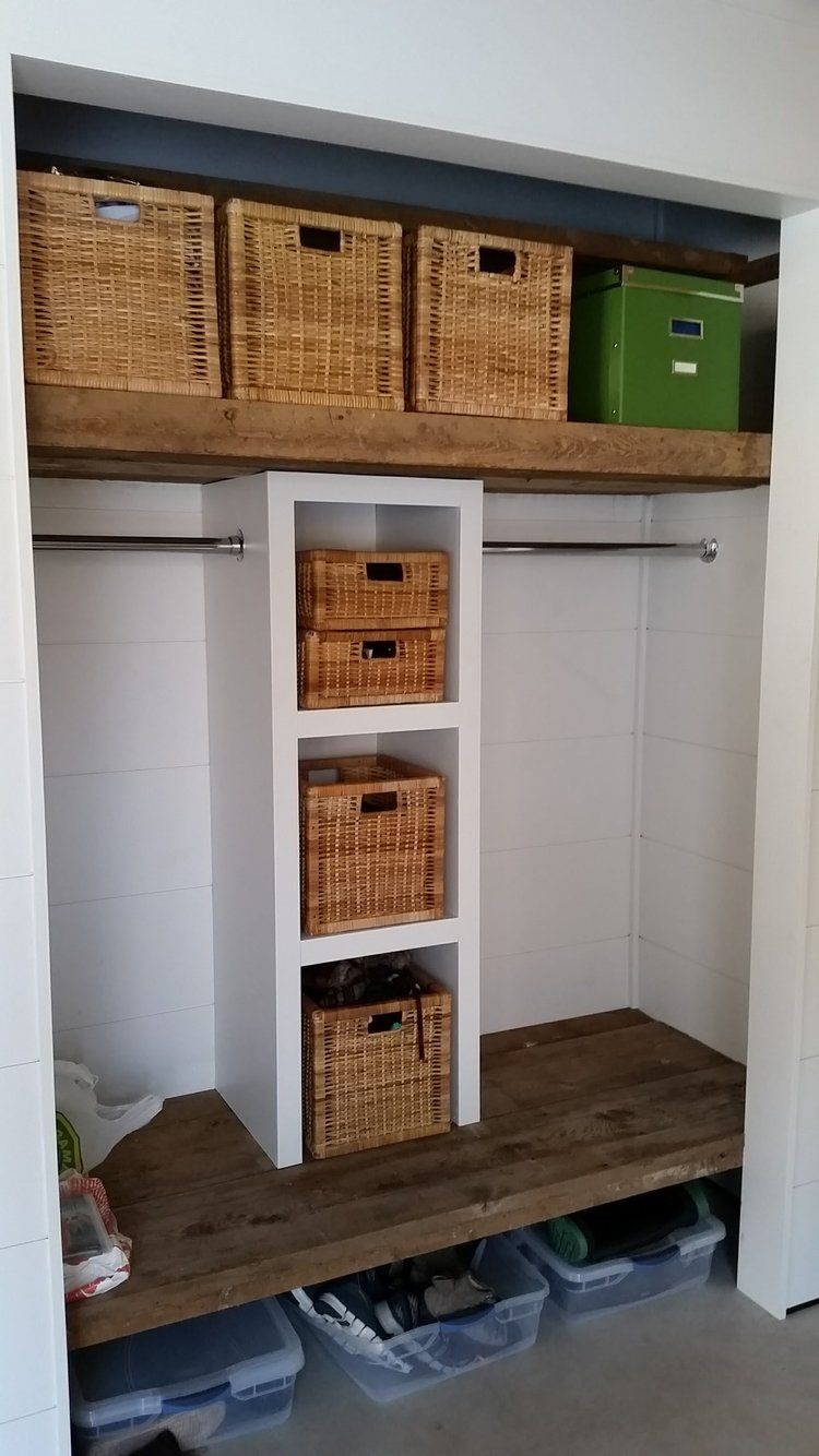 A closet with wicker baskets and boxes on the shelves.
