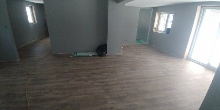 An empty room with a wooden floor and a sliding glass door.